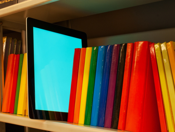 řada barevných knih a elektronické knihy čtenář na polici - Fotografie, Obrázek
