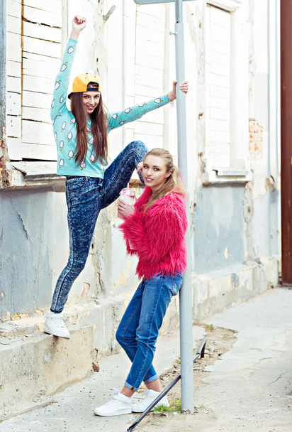 цветной модный портрет красивых девушек глэм-стрит, стоящих рядом с гранж-стеной. Держать коктейль в руке
  - Фото, изображение