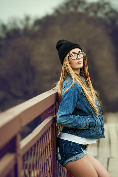 Outdoor-Lifestyle-Porträt eines hübschen jungen Mädchens, das im Hipster-Swag-Grunge-Stil urbanen Hintergrund trägt. Retro Vintage getöntes Image, Filmsimulation. - Foto, Bild