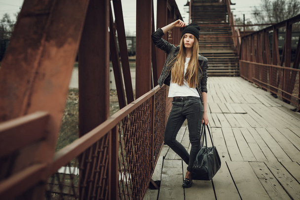 Kültéri divat életmód portréja, csinos, fiatal lány visel a csípő szajré grunge stílus városi háttér. Retro vintage tónusú kép, film szimuláció. - Fotó, kép