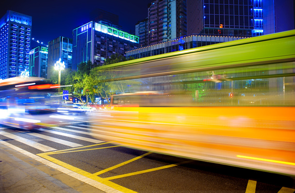 Rutas de luz de autobús borrosas y de alta velocidad en el paisaje nocturno del centro
 - Foto, Imagen