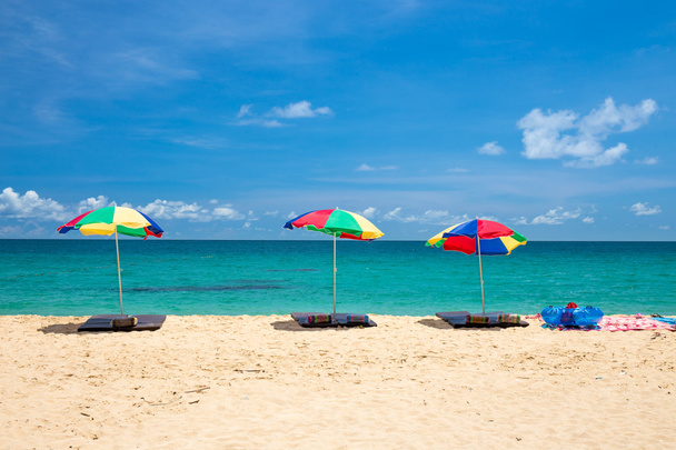 Пляжна парасолька і кільце на пляжі з блакитним небом
 - Фото, зображення