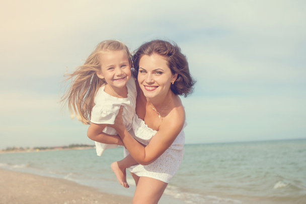Happy beautiful mother and daughter enjoying beach time - Photo, image