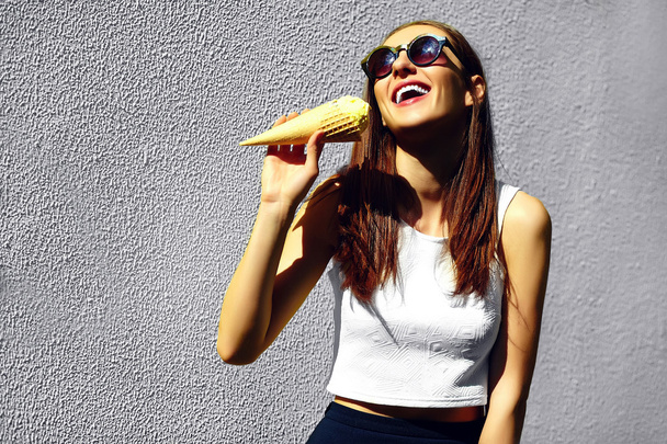 Funny stylish sexy smilingFunny stylish sexy smiling beautiful young woman model in summer bright hipster cloth  in the street eating ice cream  beautiful young woman model in summer bright hipster cloth  in the street eating ice cream near pink wall - Foto, imagen
