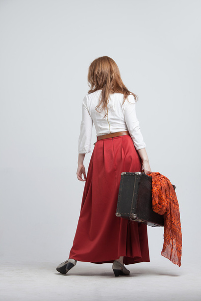 γυναίκα σε vintage κόκκινη φούστα με μια βαλίτσα - Φωτογραφία, εικόνα