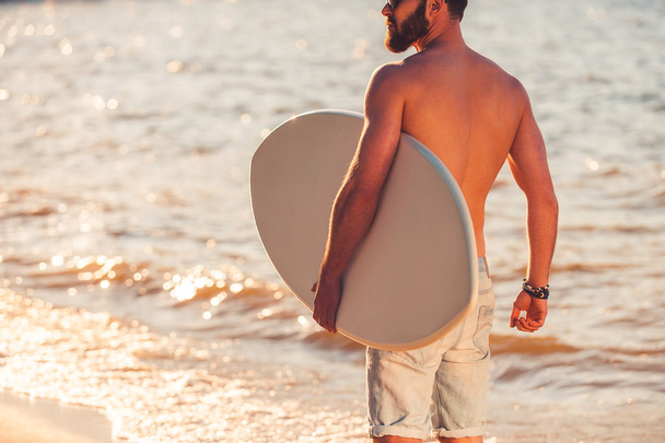 shirtless young man holding skimboard - Fotoğraf, Görsel