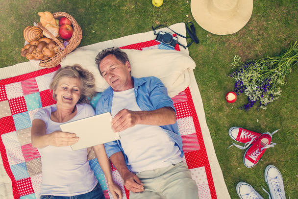Seniors with notebook having a picnic - Фото, изображение