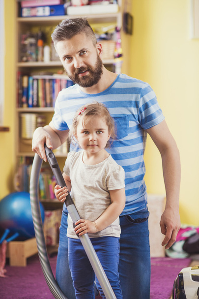 Father with his daughter vaccuming the floor - Фото, изображение