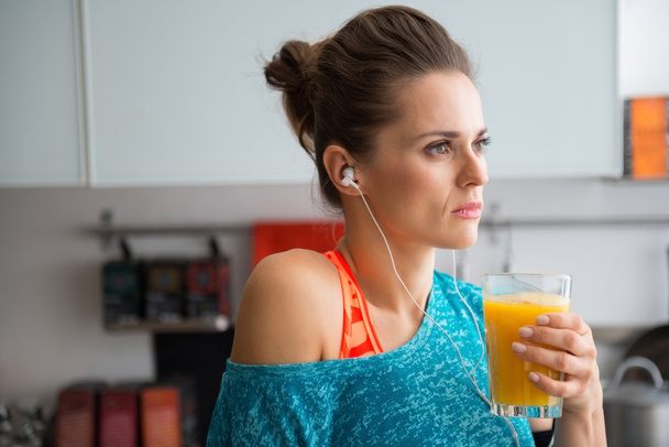 Closeup of woman in profile wearing workout gear holding juice - Foto, Bild