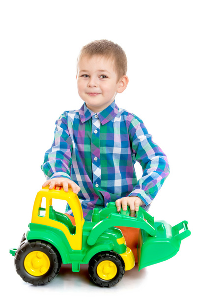 Fair-haired little boy playing with a toy tractor sitting on the - Φωτογραφία, εικόνα