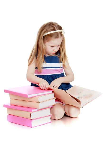 Cute long-haired Caucasian little girl reading a book sitting on - Fotó, kép