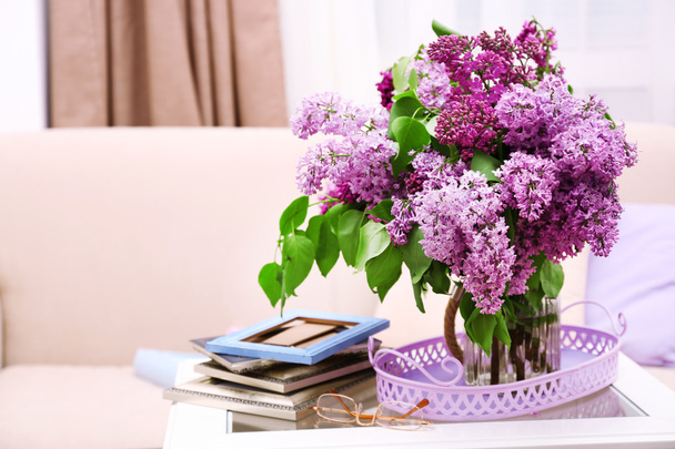 Beautiful lilac flowers in vase on table of interior background - 写真・画像