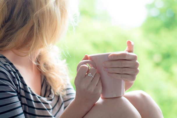 Blonde woman drinking coffee in the garden - Photo, Image