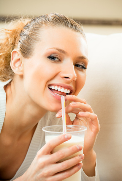 Young happy smiling woman drinking milk at home - Foto, afbeelding