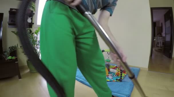 hombre piso limpio con aspiradora y bebé curioso en la alfombra de juego. 4K
 - Imágenes, Vídeo