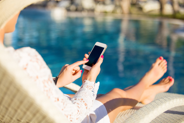 Woman sitting in deck chair and using mobile phone - Fotoğraf, Görsel