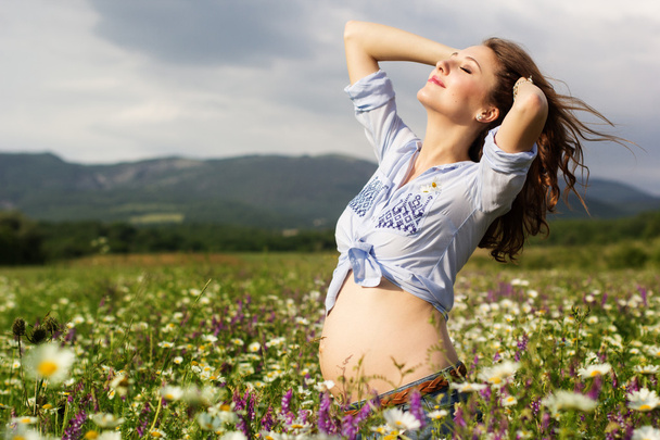 hübsche schwangere Frau im Gänseblümchen-Blumenfeld - Foto, Bild