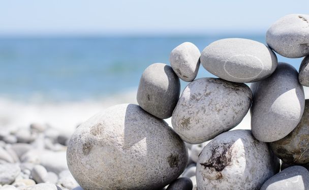 kleiner flacher Felsen balanciert auf Felswand am Strand - Foto, Bild