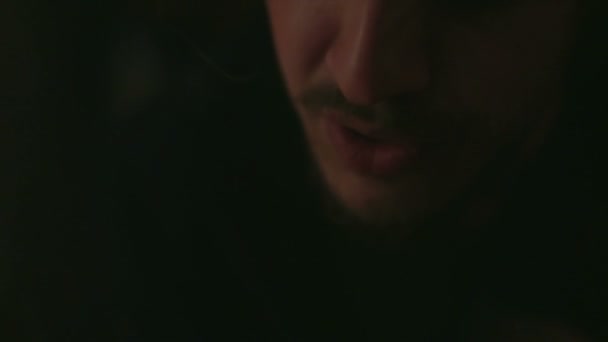 Man with berd smoking cigarette in darkness - Felvétel, videó