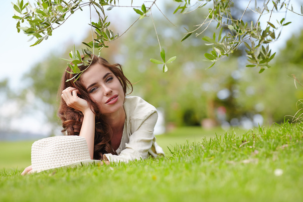 uśmiechnięta młoda dziewczyna leżąc na trawie - Zdjęcie, obraz