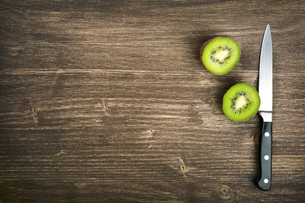 Halves of kiwi with knife on wooden background - 写真・画像