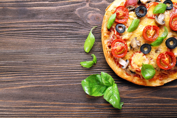 Tasty pizza with vegetables and basil on wooden background - Foto, Imagen