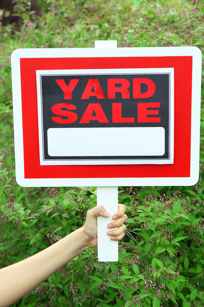 Wooden Yard Sale sign in female hand over green grass background - Fotó, kép