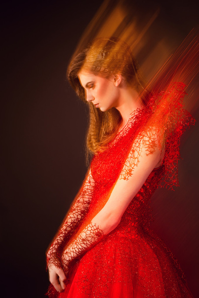 Όμορφη μόδας γυναίκας με κόκκινο φόρεμα που φωτογραφήθηκε με μικτές - Φωτογραφία, εικόνα