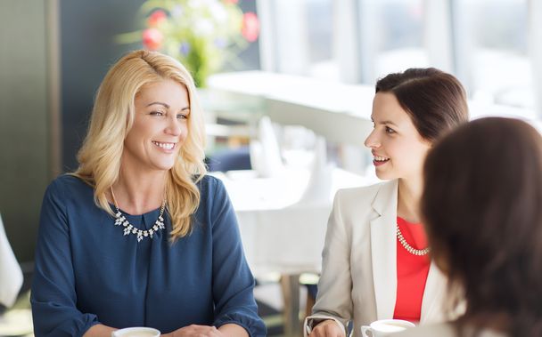 women drinking coffee and talking at restaurant - Foto, imagen