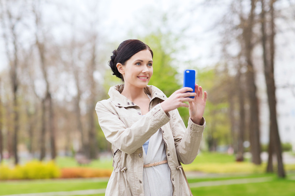 smiling woman taking picture with smartphone - Фото, зображення
