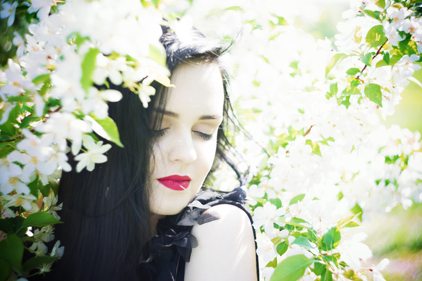 Beautiful young woman in blooming gardens - 写真・画像