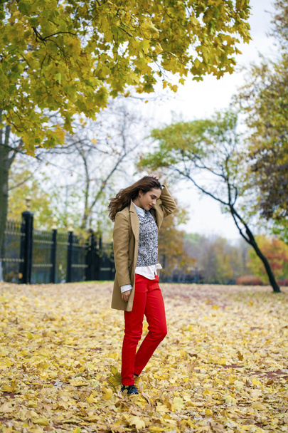 Young woman in fashion coat walking in autumn park - Photo, Image