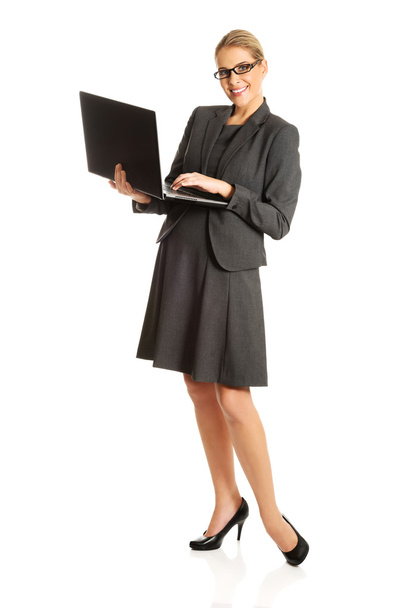 Businesswoman standing and holding a laptop - 写真・画像