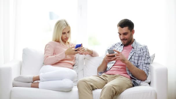 couple with smartphones texting at home - Séquence, vidéo