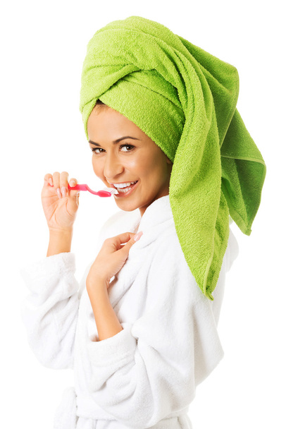 Woman in bathrobe brushing teeth - Fotó, kép
