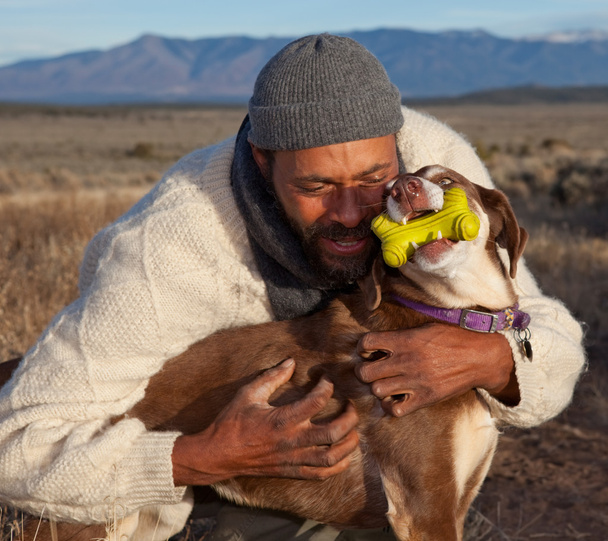 Hombre abrazando y jugando con su perro
 - Foto, Imagen
