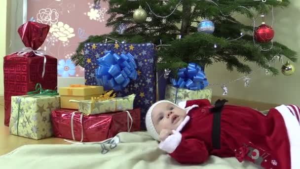 Szép baba lány hazugság közelében karácsonyfa és ajándék jelen dobozok - Felvétel, videó