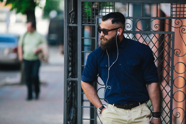 bearded man standing and listening to music - Fotó, kép