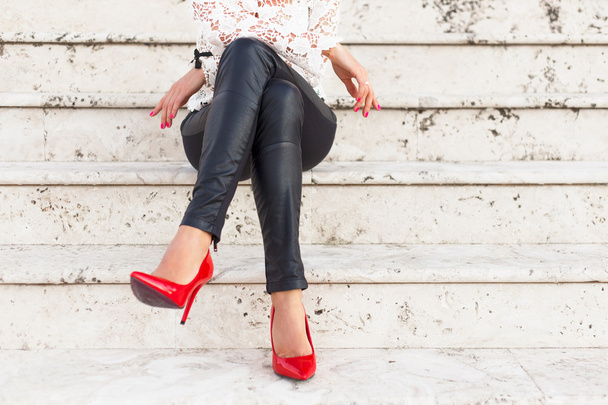 Dame avec des chaussures à talons hauts rouges assis sur les escaliers
 - Photo, image