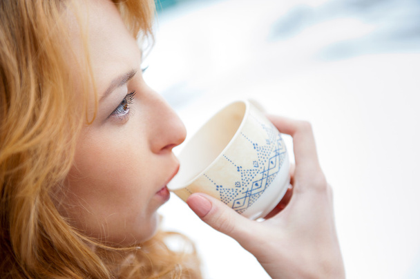 Portrait of beautiful red hair girl drinking coffee on winter ba - Fotó, kép