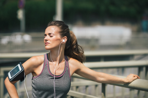 Woman runner taking a break in the sunshine listening to music - 写真・画像