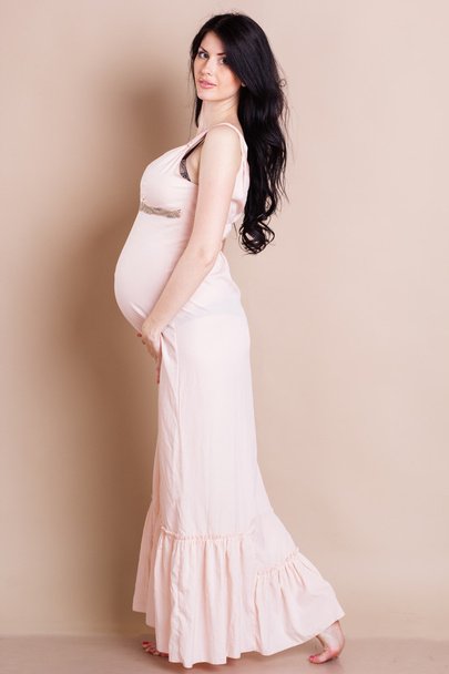 Studio portrait of beautiful pregnant woman holding her belly - Photo, image