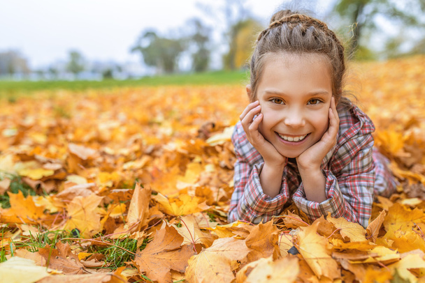 Little girl buried in autumn leaves yellow - Photo, Image