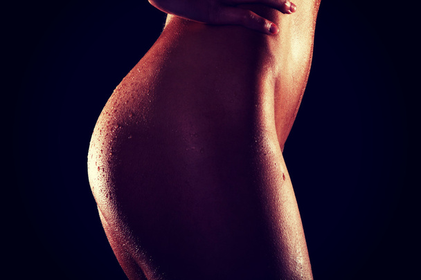 Side view naked female buttocks on dark background - Photo, image