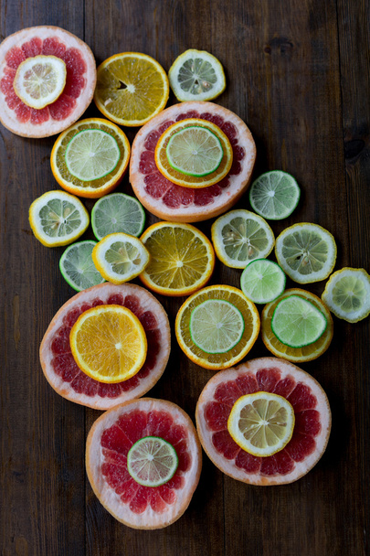 broušená citrus mix citronu grapefruitu vápna a oranžové v geometrických tvarech na tmavé dřevo rustikální pozadí rozostřený režie úhel záběru - Fotografie, Obrázek