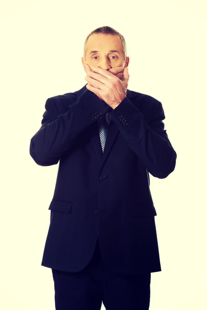 Mature businessman covering mouth  - Fotó, kép