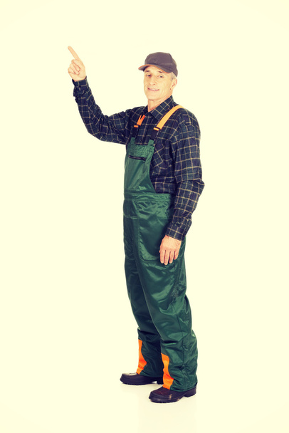 Mature gardener in uniform pointing up - Foto, Imagen