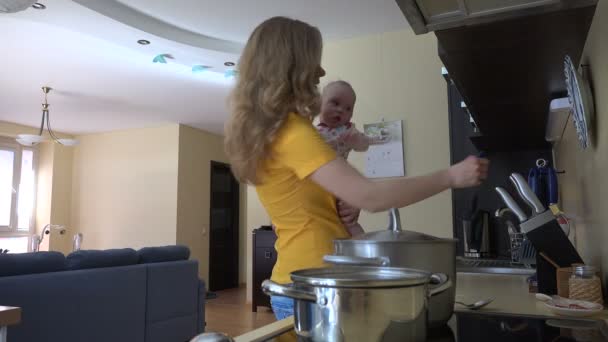 Гарненька жінка тримає маленьку дівчинку, змішує спагеті в паровому горщику. 4-кілометровий
 - Кадри, відео