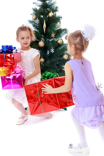 Girls sisters around the Christmas tree fuss considering boxes w - Foto, imagen