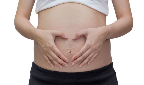 Pregnant woman forming heart out of her hands ,isolated against white background - Photo, Image